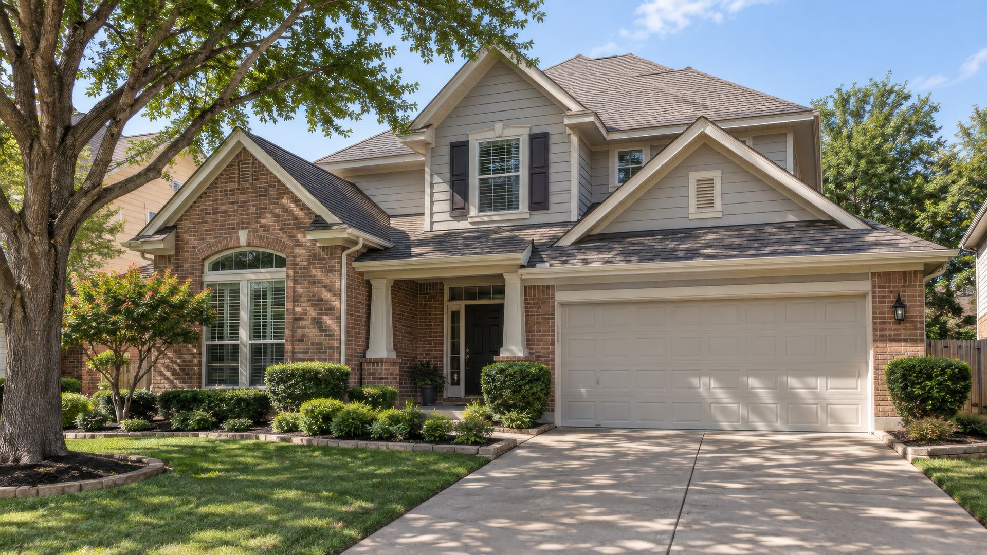 A two-story home with freshly painted lap siding, trim and gables above brick
